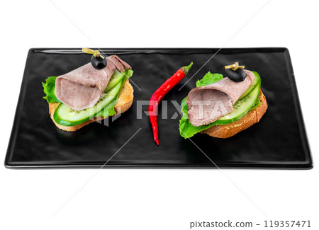 sandwiches with a slice of tender beef and vegetables on a black plate on a white background top view sandwiches with a slice of tender beef and vegetables on a black plate on a white background top view 119357471