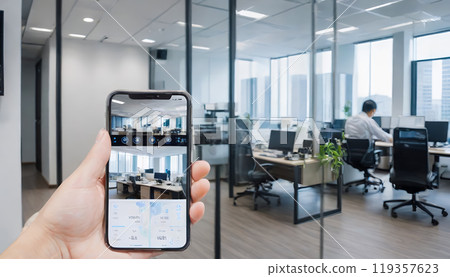 The hand of a person monitoring the room with a smartphone The hand of a person monitoring the room with a smartphone 119357623