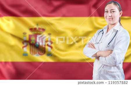 Spanish Health and Care concept. Portrait of female doctor on Spain flag. Doctor with arms crossed on Spanish flag 119357882