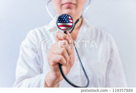 Female doctor holding stethoscope with USA flag. USA Health and Care concept Female doctor holding stethoscope with USA flag. USA Health and Care concept 119357889