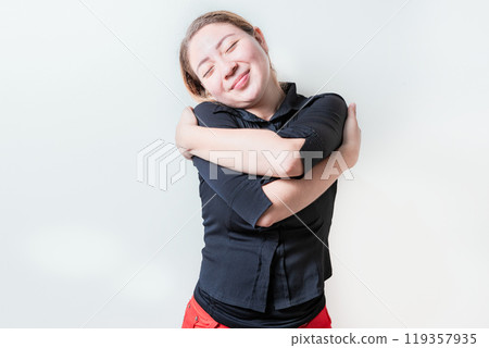 Serene girl hugging herself isolated. Positive woman hugging herself with sincere smile with grateful gesture 119357935