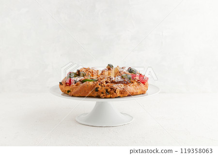 A round festive cake with candied fruit and nuts displayed on a white pedestal stand A round festive cake with candied fruit and nuts displayed on a white pedestal stand 119358063