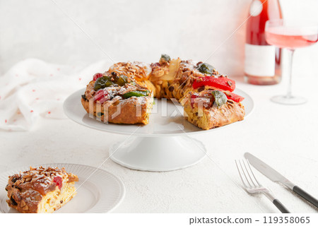 A festive wreath cake with candied fruit and nuts on a cake stand, accompanied by a glass of wine A festive wreath cake with candied fruit and nuts on a cake stand, accompanied by a glass of wine 119358065