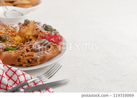 A festive cake with candied fruit and nuts, placed on a white plate with a red and white napkin nearby 119358069