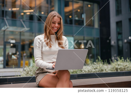 A young woman engaged in her work while using a laptop in a vibrant urban environment today A young woman engaged in her work while using a laptop in a vibrant urban environment today 119358125
