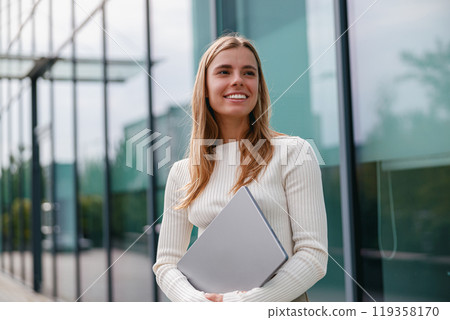 Confident Businesswoman Working on Her Laptop in a Bright, Modern Office Environment 119358170