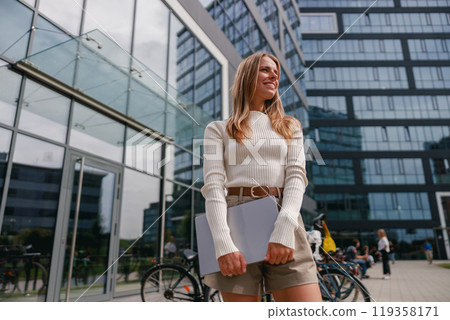A young professional stands outside a modern office building, exuding confidence in style 119358171