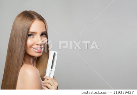 Healthy brunette lady with straight hair holding straightening iron on white background. Healthy brunette lady with straight hair holding straightening iron on white background. 119359427