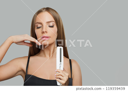 Charming smiling woman with long straight healthy hairstyle using straightening iron Charming smiling woman with long straight healthy hairstyle using straightening iron 119359439