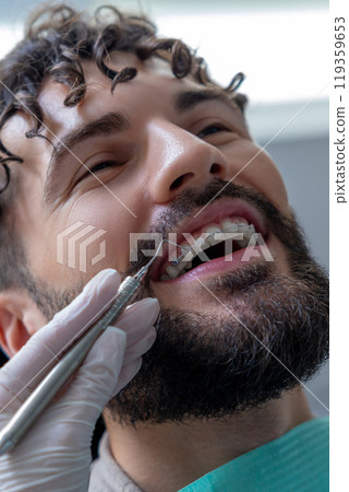 Unknown dentist doing oral examination with advanced dental equipment for patient 119359653