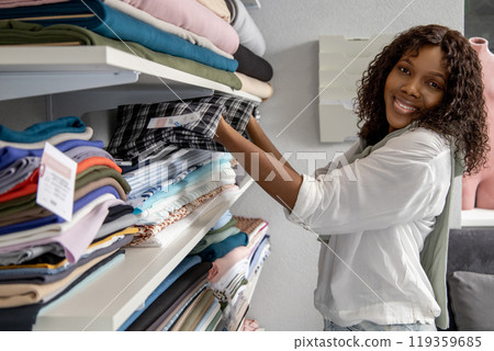 Woman choosing materials in fabric store in her sewing workshop 119359685