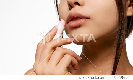 Young Korean woman taking care after lips, applying lip balm, providing moisture and hydration. Smooth, hydrated lips 119359694