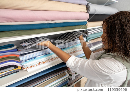 Female designer choosing fabrics for clothing in boutique Female designer choosing fabrics for clothing in boutique 119359696