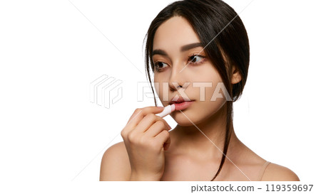 Young Korean woman taking care after lips, applying lip balm, providing moisture and hydration. Smooth, hydrated lips Young Korean woman taking care after lips, applying lip balm, providing moisture and hydration. Smooth, hydrated lips 119359697