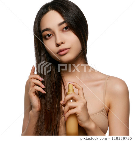 Beautiful young Korean girl taking care after hair, applying spray for hair treatment, adding shine and strength. Heat protection 119359730