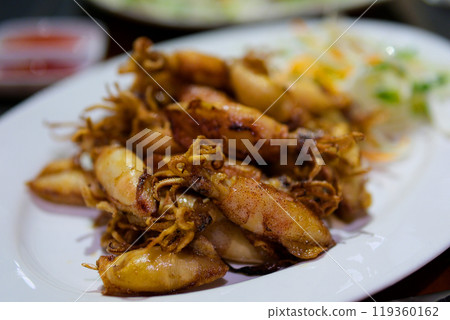 grilled octopus coming up. BBQ into yellow sauce. Eating tasty seafood in a beach restaurant. Bali gourmet. 119360162