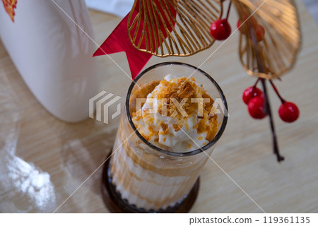 Chocolate milk pouring into a glass, splashing as it flows over, spilling on the table 119361135