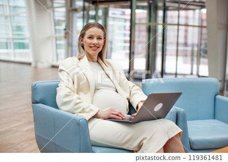 Portrait successful happy smiling Middle-aged pregnant businesswoman working indoors with a laptop. Pregnant woman in office space, Empowered female leader exuding confidence and determination 119361481