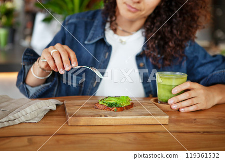 Woman enjoys avocado toast and green smoothie in a restaurant, showcasing vegan healthy food options Woman enjoys avocado toast and green smoothie in a restaurant, showcasing vegan healthy food options 119361532