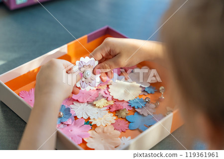 Small, colorful paper flowers in child hands, little girl creativing of 3D flowers. Child development toy Small, colorful paper flowers in child hands, little girl creativing of 3D flowers. Child development toy 119361961