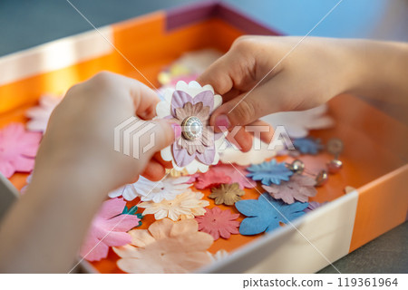 Small, colorful paper flowers in child hands, little girl creativing of 3D flowers. Child development toy Small, colorful paper flowers in child hands, little girl creativing of 3D flowers. Child development toy 119361964