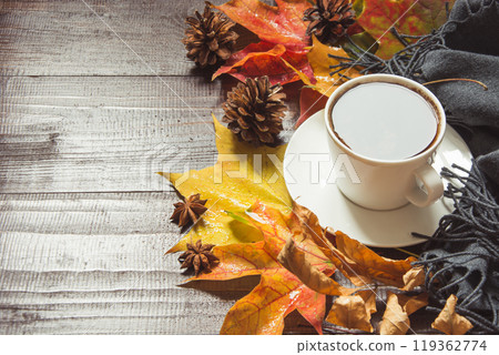 Autumn still life with cup of black coffee, cone, cinnamon, warm scarf on wooden board. Copy space. View from above. 119362774