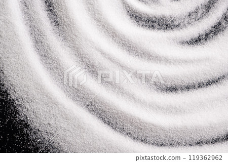 Finely ground stone white rock salt texture on black background, top view. Finely ground stone white rock salt texture on black background, top view. 119362962