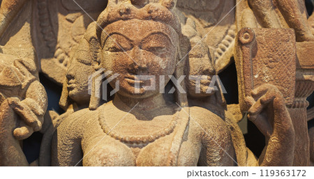 Close-up view on Ancient Stone Bas-relief Of Brahmani Or Brahmi, One Of Seven Hindu Mother Goddesses Known As Sapta Matrikas. She Is Aspect Of Adi Shakti, Possessing rajas Guna And Is Therefore Source Close-up view on Ancient Stone Bas-relief Of Brahmani Or Brahmi, One Of Seven Hindu Mother Goddesses Known As Sapta Matrikas. She Is Aspect Of Adi Shakti, Possessing rajas Guna And Is Therefore Source 119363172