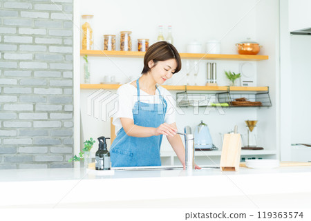 A smiling woman standing in the kitchen 119363574