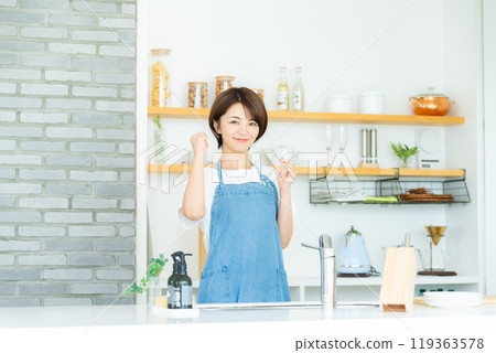 A smiling woman standing in the kitchen 119363578