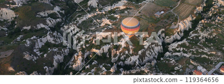 Colorful balloons floating in air above cliffs and valleys 119364656