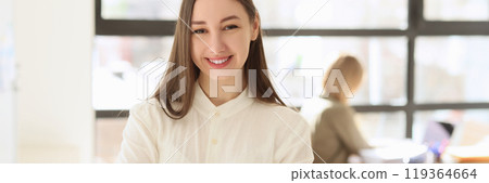 Cheerful female manager stands in office with crossed arms 119364664
