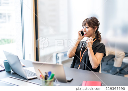 A businesswoman answering the phone with a relaxed expression 119365690