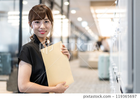 一名婦女在郵筒前拿著非標準郵件信封 119365697