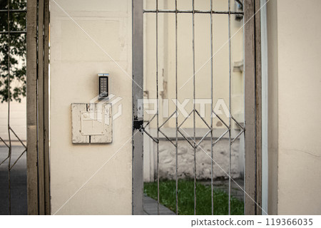 Closed metal doors in light concrete fence wall 119366035