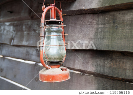 Antique rusty kerosene lantern on wooden wall. Antique rusty kerosene lantern on wooden wall. 119366116