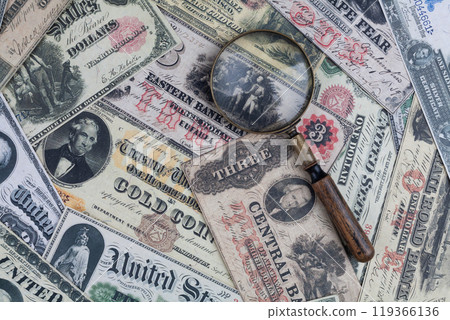 Old US banknotes and silver certificates with silver dollar coins and magnifying glass Old US banknotes and silver certificates with silver dollar coins and magnifying glass 119366136