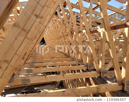 Perspective view down rows of wooden trusses, emphasizing the geometric layout and precision of the construction 119366307
