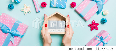 Top view of female hands holding calendar on blue background. The first of January. Holiday decorations. New Year concept 119368206
