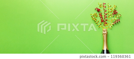 Creative flat lay composition with bottle of champagne and space for text on color background. Champagne bottle with colorful party streamers. holiday or christmas concept Creative flat lay composition with bottle of champagne and space for text on color background. Champagne bottle with colorful party streamers. holiday or christmas concept 119368361