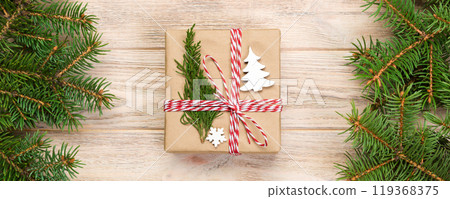 Christmas background with fir tree and gift box on wooden table. Top view with copy space for your design 119368375