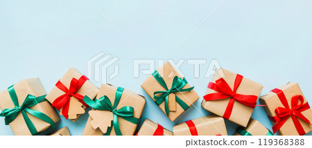 wrapped christmas or other holiday handmade present in paper with colored ribbon. Present box, decoration of gift on colourfull table, top view with copy space 119368388