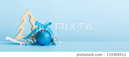 Christmas ball with decorative wooden tree on colored background. decoration bauble with ribbon bow with copy space 119368412