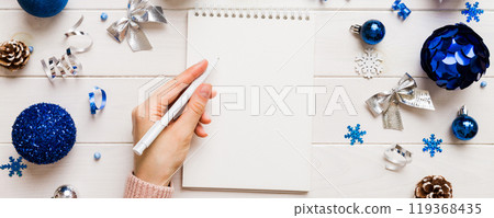 Woman writing Christmas to do list on notebook on colored background with xmas decorations 119368435