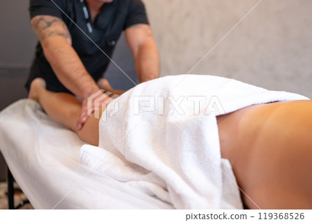 The hands of the masseur massage the legs of woman in the spa. 119368526