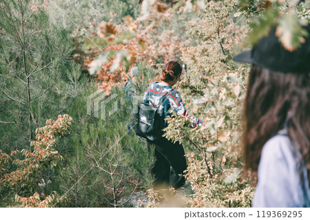 Sports and tourism. The woman descends the slope, holding on to the branches of the bushes. Rear view Sports and tourism. The woman descends the slope, holding on to the branches of the bushes. Rear view 119369295