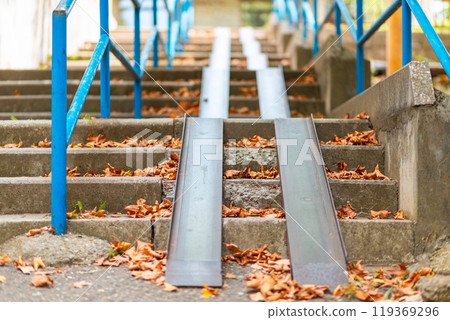 Steps with a blue railing and ramp, covered with autumn leaves. Bottom view. Nobody Steps with a blue railing and ramp, covered with autumn leaves. Bottom view. Nobody 119369296