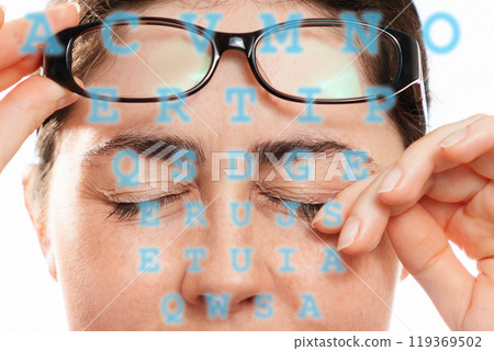 Close-up of woman's face scratches her painful eyes, taking off her glasses. Blue letters in the foreground. The concept of unhealthy eyes and vision 119369502