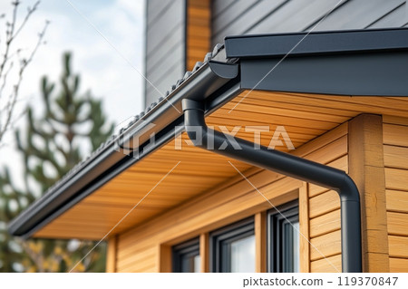 Close up of a gutter system on a modern home with a wooden facade 119370847