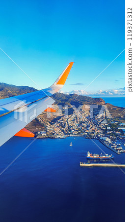 View from the airplane window on the wing and the island of Madeira, Portugal. Concept of air travel to Madeira to exotic countries 119371312